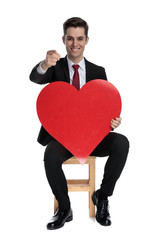 Attractive businessman pointing forward and holding a heart shape