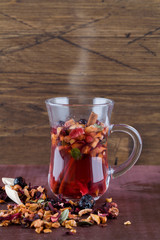 fruit hot red tea in glass cup with cinnamon on wood background.
