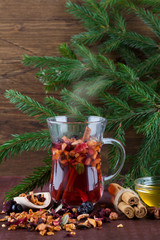 Winter fruit hot tea with honey, cinnamon and christmas tree branch on wood background.