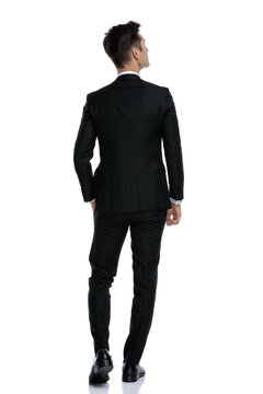 back view of young elegant man in tuxedo looking up
