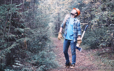 Male lumberjack in the forest. A professional woodcutter inspects trees for felling.