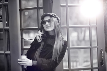 Beautiful young girl in a phone booth. The girl is talking on the phone from the payphone. English...