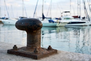 Detalle de un bolardo de amarre con barcos de fondo