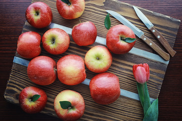 Fresh apples on a wooden board. Harvest of red apples. Fruits and cinnamon on the table.