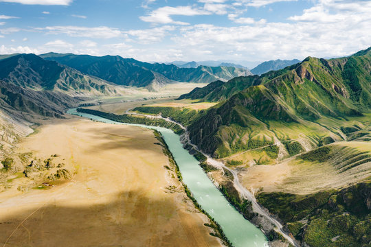 Turquoise Katun River in deserted steppe valley and highway R256 Chuysky Trakt between green mountain ranges of Altai, aerial view. Nature landscape near Maly Yaloman, Altai Republic, Siberia, Russia