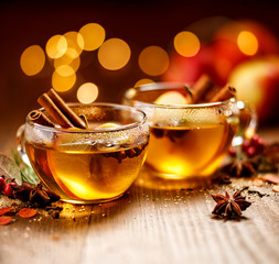 Mulled cider with apple slices, cinnamon, cloves, anise stars and citrus fruits in glass cups on a...