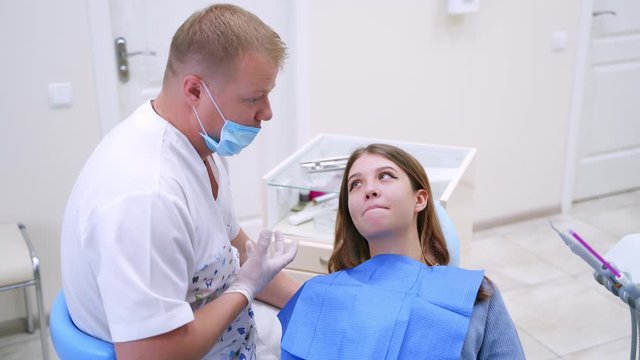 Dentist talks to a female patient. Professional doctor explains female patient how to look after her teeth. Beautiful woman visits stomatologist in clinic.