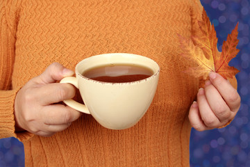 hot tea, coffee in female hands with yellow leaves, autumn mood concept