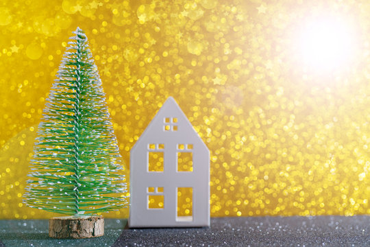 Green christmas tree on shiny background. Beautiful bokeh. Little white house.