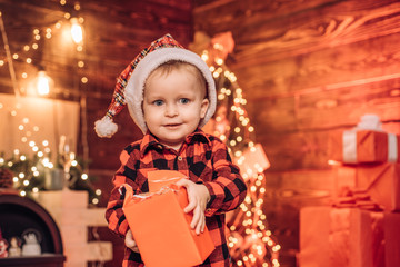 Fototapeta na wymiar Little blue eyed baby Santa boy received his New Year present. Happy christmas. Home. Shopping sale. Family holiday. Happy family couple. Christmas shopping concept.