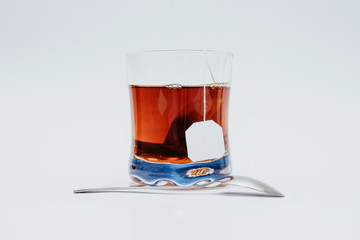 Glass of tea isolated on a white background with a spoon. The concept of drinking tea, using glasses. Enjoying tea instead of coffee.