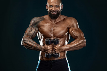 Fototapeta na wymiar Strong and fit man bodybuilder. Sporty muscular guy with dumbbells. Spot and fitness motivation.