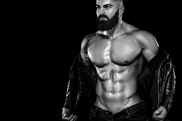 Fototapeta na wymiar Men's fashion concept. Close-up portrait of a brutal bearded man topless in a leather jacket. Athlete bodybuilder on black background.