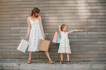 Beautiful girl in a summer city. Lady with shopping bags. Mother with daughter in stylish clothes