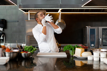 young attractive male cook blows up his protective glove jokes and has fun in the professional...