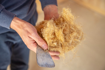 Hand of a worker holding hemp wool, an ecological insulation material which is environmentally...