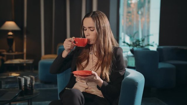 Business woman drinking tea in hotel lobby. Businesswoman drinking coffee