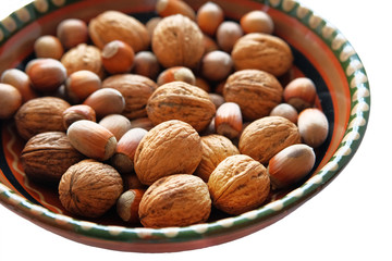 Nuts in a plate isolated on white background. Healthy vegan vegetarian snack or ingredient for cooking, hazelnuts and walnut. Close up.