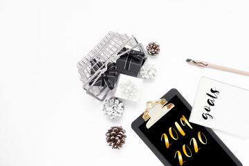 New year goal, plan, golden text 2019 2020 on black clipboard with paper blank, white, black gift boxes in shopping basket, pine cone. Motivation, inspiration concept idea, design flat lay, copy space