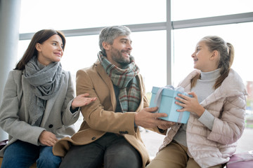 Happy parents congratulating their daughter on holiday and passing her gift