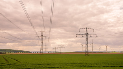 Überlandleitungen mit Windpark im Hintergrund im Abendrot