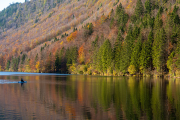 Seeufer am Langbathsee mit bunten Herbstwald und Kajak bei Sonnenuntergang