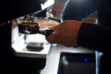process of making coffee, the barista presses ground beans, the guy makes coffee in a coffee shop