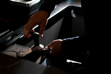 process of making coffee, the barista presses ground beans, the guy makes coffee in a coffee shop