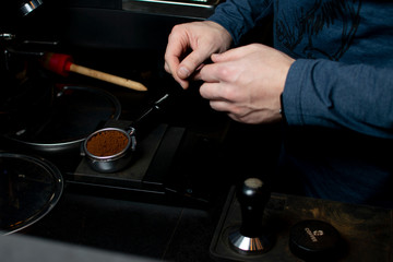process of making coffee, the barista presses ground beans, the guy makes coffee in a coffee shop