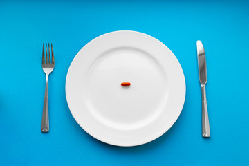 A small tablet in a plate. Medical concept. Eat pills instead of food.
