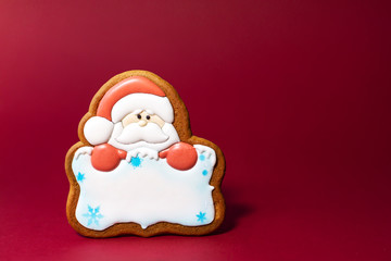 gingerbread cookie of Santa portrait with copyspace on red background. Traditional Christmas food. Christmas and New Year holiday concept.