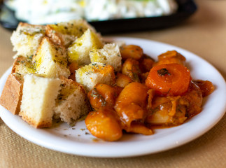 Greek food, cooked white beans with carrot and tomatoes served with roasted with olive oil and herbs bread