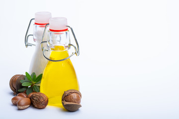 Skin and hair care product, creme or shampoo made from natural argan or macadamia oil in bottle and argan and macadamia  nuts isolated on white background