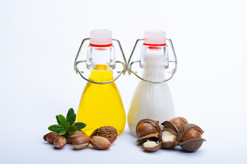 Skin and hair care product, creme or shampoo made from natural argan or macadamia oil in bottle and argan and macadamia  nuts isolated on white background