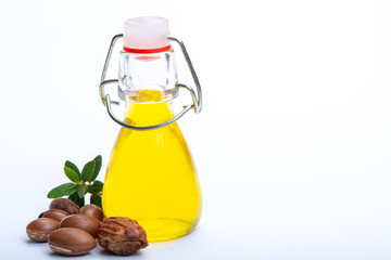Skin and hair care product, natural argan oil in bottle and argan nuts isolated on white background