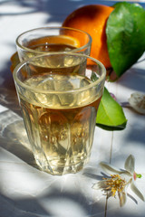 White wine served outside in garden on white table with fresh orange in sun lights