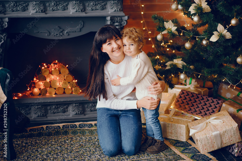 Sticker Beautiful mother in a white sweater. Family in a christmas decorations. Little boy in a room