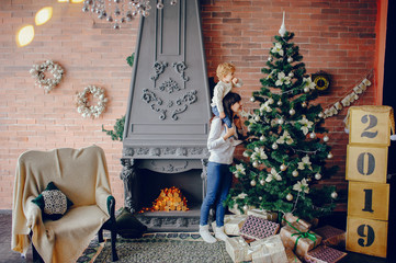 Beautiful mother in a white sweater. Family in a christmas decorations. Little boy in a room