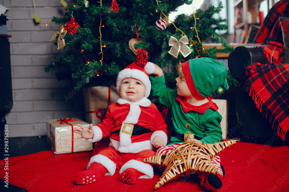 Poster Cute little boys in a christmas costumes. Children by the christmas tree