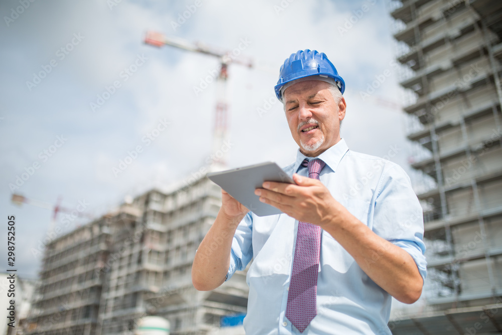 Wall mural site manager using his tablet in front of a construction site