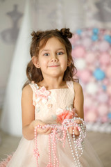 Little girl in a white dress plays with beads
