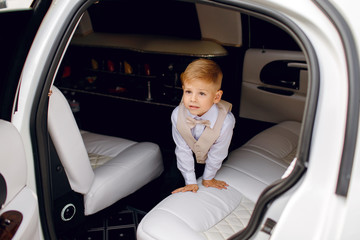 Little elegant boy stands in a limousine, a rich child