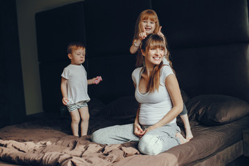 Beautiful mother with daughter and son. Family sitting in the room on a bed