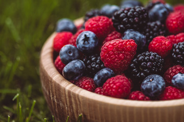 raspberries and blackberries in wood bowl on table, vintage