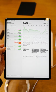 PARIS, FRANCE - NOV 7, 2018: Front view POV personal perspective experiencing new Apple iPad Pro tablet with Stock MArket app with graph of AAPL quotation and new Apple Pencil on the side