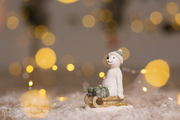 Decorative Christmas-themed figurines. The statuette of a polar bear sits on a wooden sled, in a...