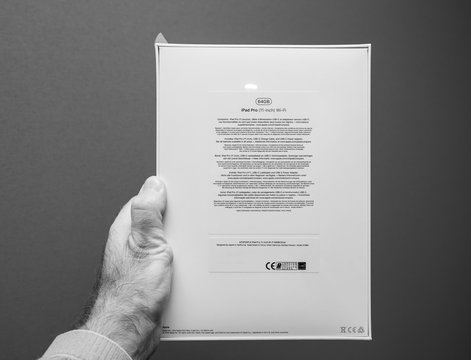 PARIS, FRANCE - NOV 14, 2018: Man Holding POV The Rear Packaging Latest IPad Pro By Apple Computers Tablet Retail Box Against Gray Background