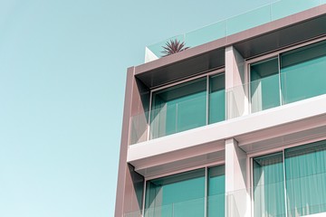 Edificio residencial minimalista con grandes ventanas de cristal y un cielo azul de fondo