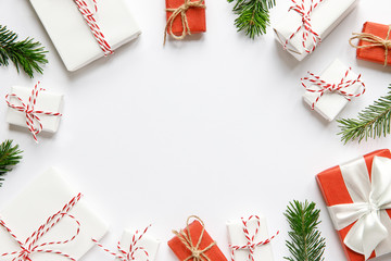 New Year composition. Christmas background with red and white wrapped gifts boxes with ribbon, fir branches on white background, copy space. Winter holiday pattern. Top view, flat lay. 