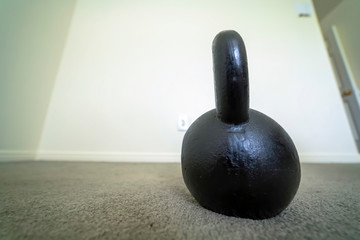 Fototapeta na wymiar Close up of a kettlebell on the floor with gray carpet inside a fitness room